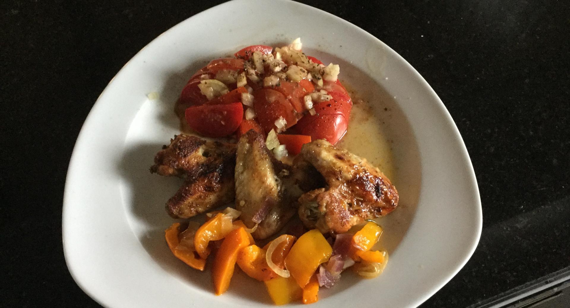 Pouletflügeli grilliert auf Paprikagemüse mit Tomatensalat