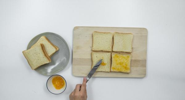 Vier Toastscheiben mit etwas Aprikosenkonfitüre bestreichen.