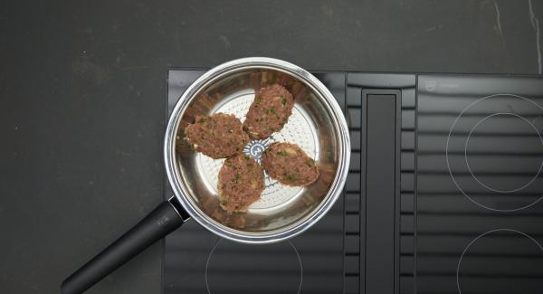 Sobald der Audiotherm beim Erreichen des Brat-Fensters piepst, auf niedrige Stufe schalten, Häfte der Bifteki in die HotPan geben und den Deckel auflegen.