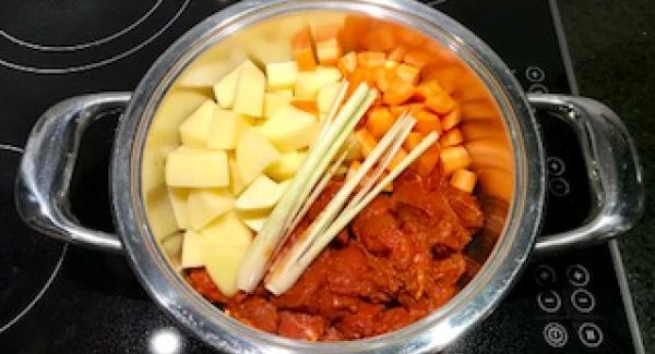 Das marinierte Rindergulasch, Kartoffeln und Karotten in den kalten Topf geben.