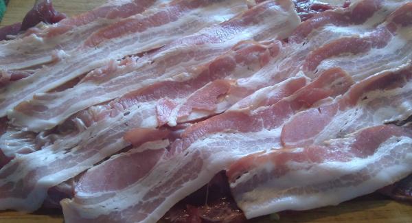 Das Fleisch plattieren, mit Salz und Pfeffer würzen. Mit dem Bacon belegen. Auf den Bacon die Füllung ausbreiten und zusammen rollen. Mit Küchengarn binden.
