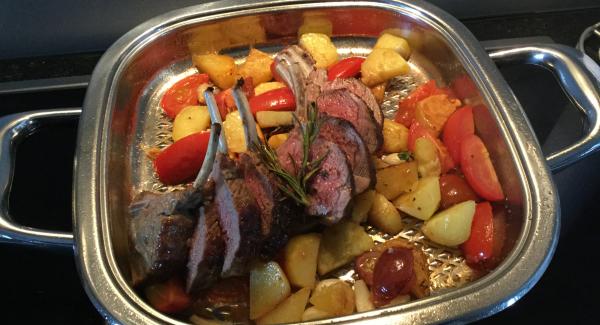 Lammracks herausnehmen und kurz abstehen lassen. Die Tomatenkartoffeln bei erhöhter Hitze fertig braten und abschmecken. Lammracks aufschneiden und zurück auf die Kartoffeln legen. Im umgekehrten Servierdeckel zu Tisch bringen. Servieren.