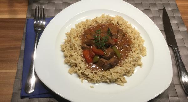 Im umgekehrten Servierdeckel zu Tisch bringen die zwei Esslöffel Sauerrahm auf das Stroganoff geben und servieren.