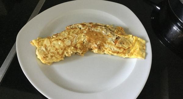 Eierfladen mit Hilfe einer flachen Bratkelle überschlagen und noch etwas Farbe annehmen lassen. Auf einen vorgewärmten Teller stürzen und servieren. Die zweite Omelette gleich herstellen.