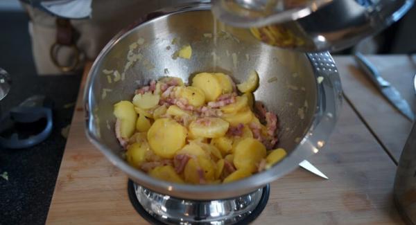 Die Gemüsebrühe, Speck und Zwiebeln nach und nach zu den Kartoffeln geben. Wichtig: Die Kartoffeln nicht mit einem Löffel umrühren, sondern alles vorsichtig schwenken.
