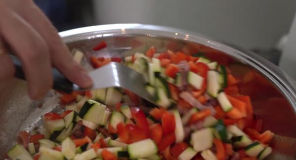 Sobald der Speck leicht angebraten ist, eine ausgedrückte Knoblauchzehe dazugeben. Anschließend die Zucchini und die Paprika dazugeben.