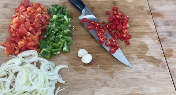 Die Zwiebeln und den Knobloch schälen. Anschließend die Zwiebel und Chilischoten in Scheiben, die Paprika in Würfel schneiden.