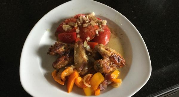 Tomatensalat auf Teller anrichten, grillierte Pouletflügeli dazulegen und mit dem Gemüse dekorieren.