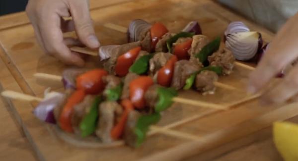 In der Zwischenzeit können die Spieße vorbereitet werden. Dabei einfach Zwiebel, Fleisch, Tomate, Fleisch, Peperoni, Fleisch, Tomate, Fleisch, Peperoni aufspießen.