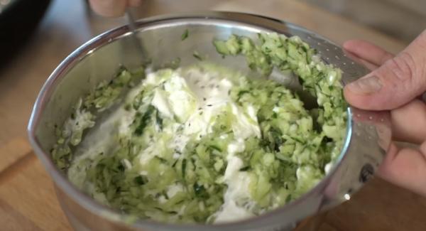 Die zerkleinerte Salatgurke in eine Schüssel geben und anschließend gut salzen. Danach 400g griechischen Joghurt und 100g saure Sahne dazugeben.