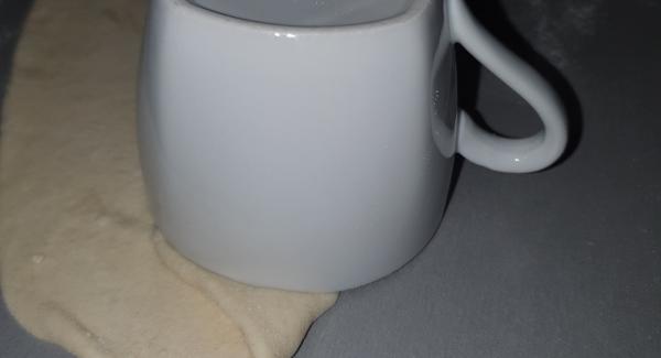 Drücken Sie den Teig mit der Hand rundum fest und stechen dann mit einer Kaffeetasse die Nudel wie am Bild aus: