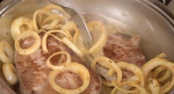 Die Zwiebeln zu dem Fleisch geben.