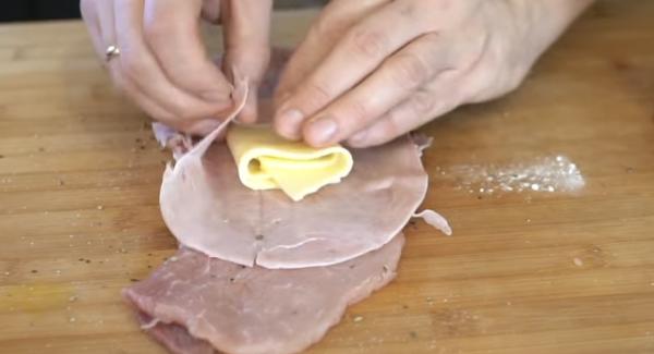 Den Kochschinken und den Käse auf das Schweineschnitzel legen und rechteckig falten.