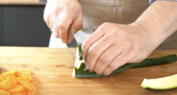 Eine Zucchini in kleine Würfel schneiden.