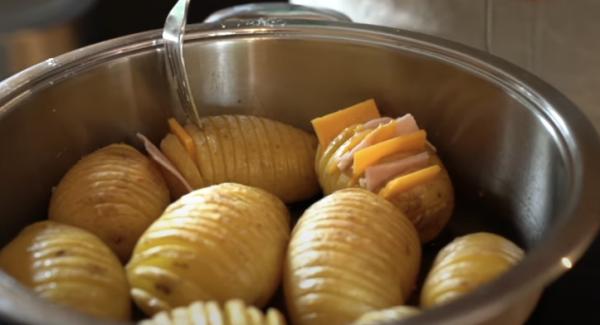 Sobald die 30 Minuten abgelaufen sind, den Käse und den Kochschinken mithilfe einer Gabel zwischen den Rillen in den Kartoffeln stecken. ( Bitte seid vorsichtig, die Kartoffeln sind sehr heiss!)