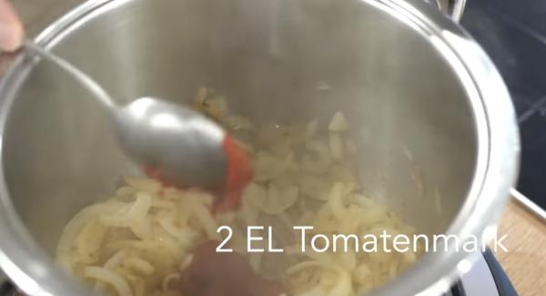 Sobald die Zwiebeln glasig sind, 2 EL Tomatenmark dazugeben. Alles umrühren mit einem Holzlöffel.