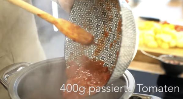 Sobald das Tomatenmark angebraten ist, 400g passierte Tomaten dazugeben.