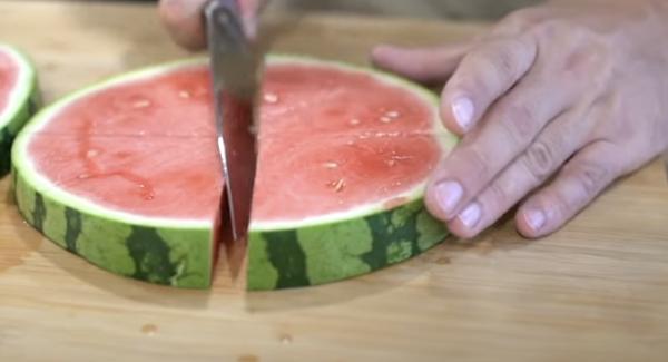 In der Zwischenzeit die Wassermelone in dicke Scheiben schneiden und anschließend die Stücke vierteln.