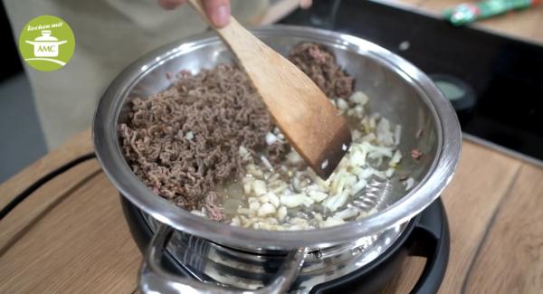 Sobald sich das Hackfleisch löst, gut umrühren und zur Seite schieben und die Zwiebeln mit anrösten.