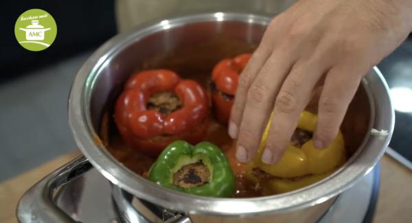 Die gefüllte Paprika in die Soße reinsetzen, Paprikadeckel drauf setzen (ohne Strunk).