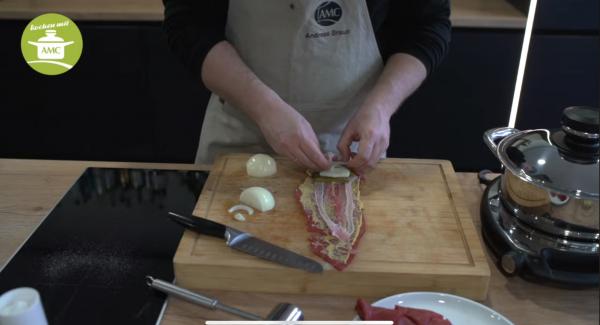 Die Rinderrouladen mit jeweils 3 Scheiben Speck, einer kleinen Essiggurke (in Scheiben geschnitten) und etwas Zwiebel belegen und gut zusammen Rollen (Seiten zusammenklappen, damit eine Art Tasche entsteht und anschließend eng zusammen Rollen)